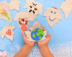 Child created Earth planet from plasticine and card from paper and natural leaves. Protection of...