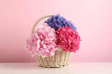 Bouquet with beautiful hortensia flowers in wicker basket on white wooden table