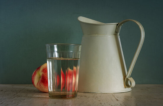 Still life with a glass of water, a peach and a jug. Vintage.