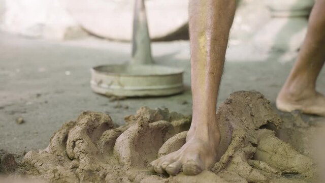 Close up of legs preparing or mixing clay before making pot or earthenware - Traditional way of crushing or wedging the pottery caly to make it bubble free.