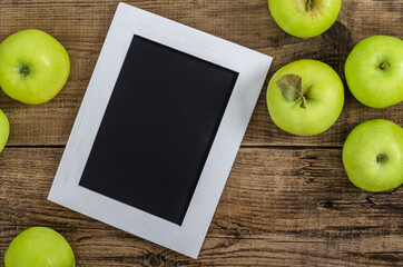 Ripe green apples with frame on an wooden background.