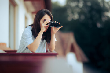 Curious Woman Holding a Pair of Binocular Spying on her Neighbors - obrazy, fototapety, plakaty
