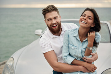 Happy european couple standing at cabriolet car