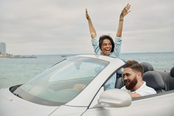 Young european couple riding in cabriolet car