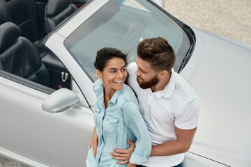 Happy european couple standing at cabriolet car