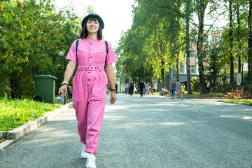 A young girl with a camera walks in a city park.