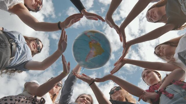 Earth conservation concept. 11 girls surround the rotating earth globe with their palms.