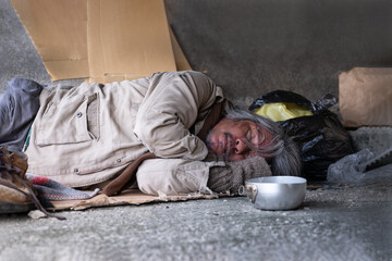 Elderly man homeless dirty with gray hair wear sweater and glasses sleeping on cardboard box to...