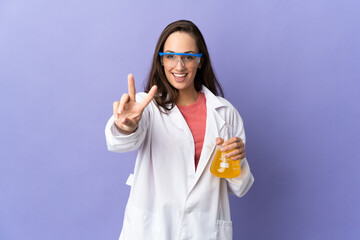 Young scientific woman over isolated background smiling and showing victory sign
