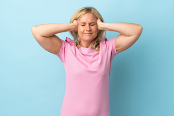 Middle age woman isolated on blue background frustrated and covering ears