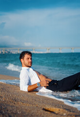 Masculine man relaxing on wet beach in evening