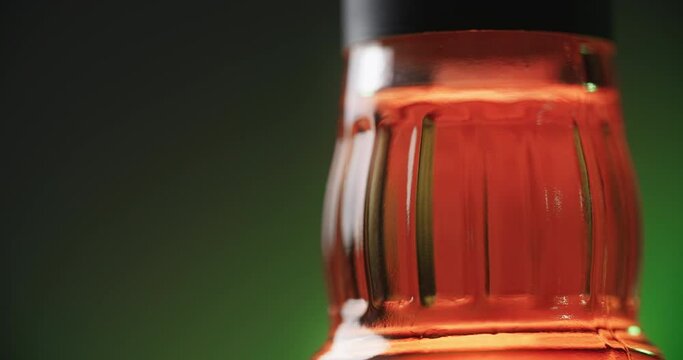 WARSAW, POLAND - SEPTEMBER 10, 2021: close up shot of the bottle of Jim Beam bourbon that is spinning around on the greenish background, 4k 60p Prores HQ