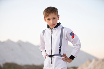 A young boy dressed as an astronaut against the backdrop of white mountains and blue sky.
