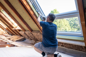 Craftsman caulking a new window in the attic.