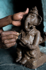 Fototapeta na wymiar Close up of artist hands making clay ganesh idol for ganesha festival - concpet of religious festival preparations