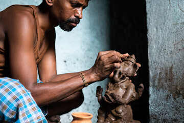 Focus on hands, Concentrated artist making clay ganesh idol for ganesha festival - concpet of hindu...