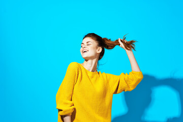 woman in yellow sweater posing fashion hairstyle blue background