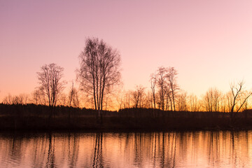 Beautiful autumn natural park with a river, trees at sunset.