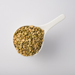 white dish cup full of green lentil. isolated on white. Top view