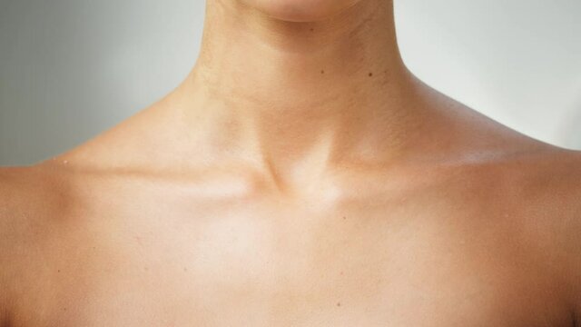 Young woman clavicles close-up, model with smooth healthy skin. Female shoulders, naked body. Beauty and body care concept. Unrecognizable person with bare neck and chest on white background.