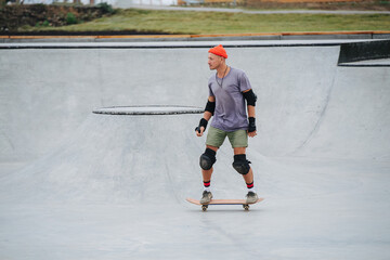 Mature skater in a watch cap riding on a skateboard in a skate park