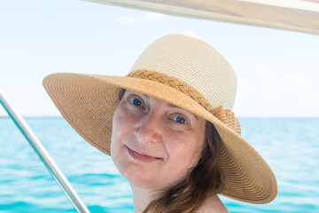 Summer portrait of a beautiful woman 40 years old in a straw hat at the sea.