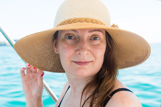 Summer portrait of a beautiful woman 40 years old in a straw hat at the sea.