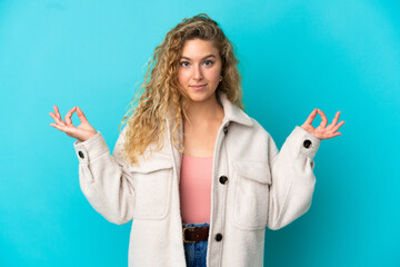 Young blonde woman isolated on blue background in zen pose