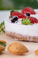 Close up of White cake with coconut, almond milk and nuts, garnished with fresh strawberries and mint, selective focus. Healthy, low-calorie and low-carb dessert. Healthy eating, nutrition and diet