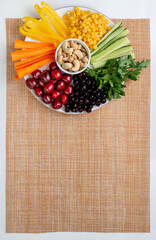 The set of colorful vegetable, fruit and nut snacks on the plate, vegetarian snack decorated in a rainbow spectrum. Healthy eating, nutrition and diet background concept. Top view, flat lay