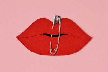Paper lips cut-out closed with safety pin - Violence against women concept
