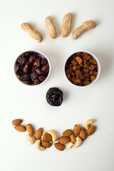 Set of raisins, rose hips, peanuts, almonds, cashews and prunes fomed in cute face shape. top view on white background