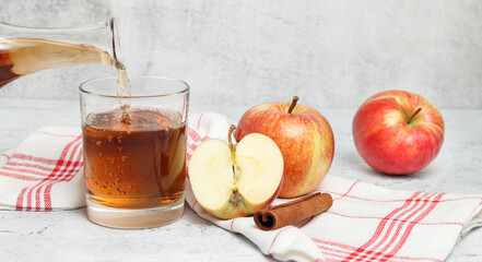 Banner with apple juice pouring in the glass on white concrete background