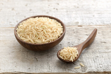 closeup of uncooked long brown rice on the wooden table