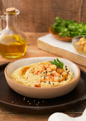Chickpea hummus dip in bowl on wooden table. Copy space, selective focus. Vegetatian healthy food concept.