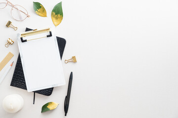 Top view paper clipboard, notebook, office stationery on white desk table. Elegant feminine...