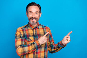 Photo portrait man smiling pointing finger copyspace wearing checkered shirt isolated vibrant blue color background