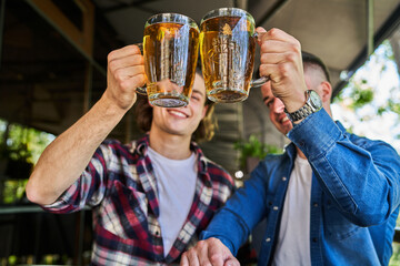 Two glasses of beer in man hands in pub.