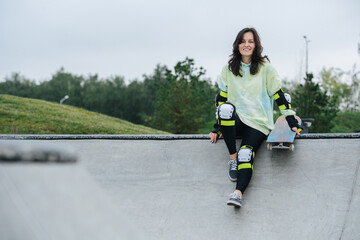 Smiling beautiful woman skater resting on a deck. Nature in background.