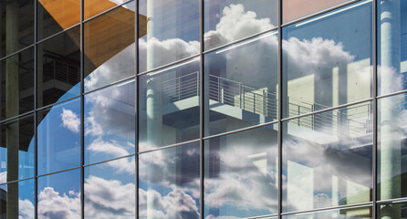 cloudy sky reflected in a modern glass facade.
Image detail of a contemporary corporate building.