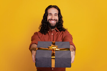 Fototapeta premium Portrait of cheerful friendly guy give you new present box on yellow background