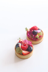 Modern Fruit Tartlets garnished with flowers, on a white background.