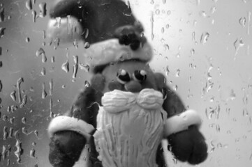 Figure of Santa Claus on the background of a wet window.