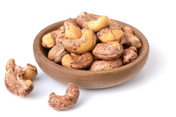 roasted cashew nuts with peel in the wooden plate, isolated on the white background