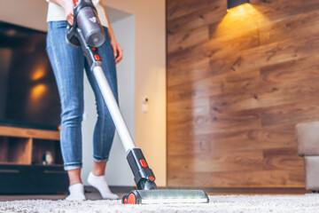 oman cleaning floor and carpet with cordless vacuum cleaner at home. - obrazy, fototapety, plakaty