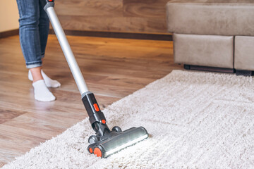 oman cleaning floor and carpet with cordless vacuum cleaner at home.