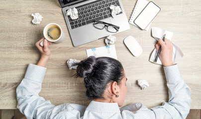 Top view of tired, overwoked businesswoman, office worker, lying on the desk with laptop, coffee and papers.