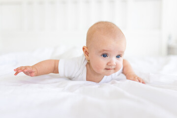 Portrait of cute and smiling four month old baby girl playing on the bed in her room. Happy and dry kid. 