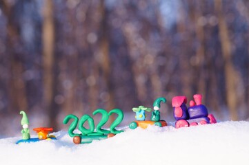 Toy train with Christmas toys and the date 2022 in the winter forest.