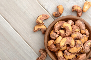 roasted cashew nuts in the wooden bowl on the table, top view